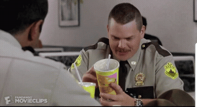 A Man In A Sheriff 'S Uniform Is Holding A Cup With A Straw And A Drink In It GIF