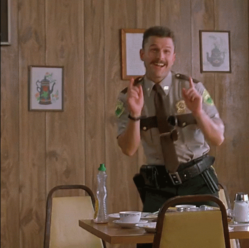 A Man In A Sheriff 'S Uniform Is Sitting At A Table With The Words Ah Ha Ha Written On It GIF