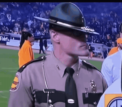 A Man In A Sheriff 'S Uniform Is Standing On A Football Field GIF