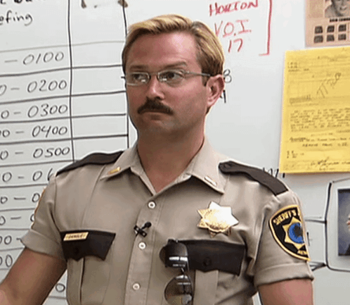 A Man In A Sheriff 'S Uniform Stands In Front Of A White Board With Numbers On It GIF