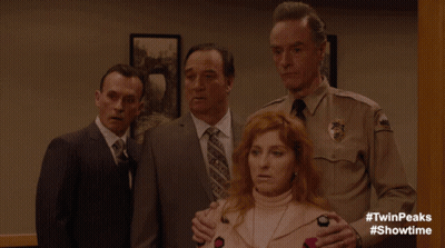 A Man In A Sheriff 'S Uniform Stands Next To A Woman In A Pink Sweater GIF
