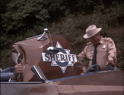 A Man In A Sheriff Uniform Is Standing Next To A Damaged Sheriff 'S Car GIF