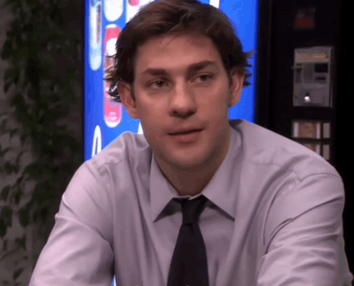 A Man In A Shirt And Tie Is Sitting In Front Of A Pepsi Machine GIF