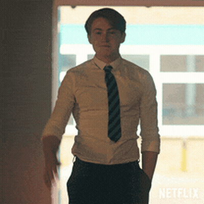 A Man In A Shirt And Tie Is Standing In Front Of A Netflix Sign GIF
