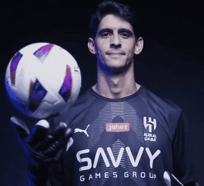 A Man In A Shirt That Says Savvy Games Group Holds A Soccer Ball GIF