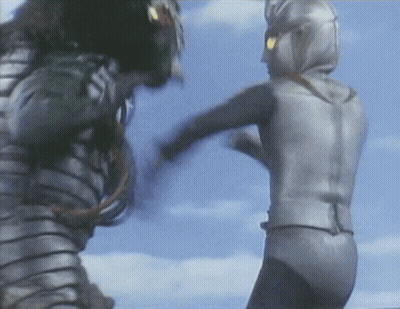 A Man In A Silver Suit Kicks Another Man In A Black Suit GIF