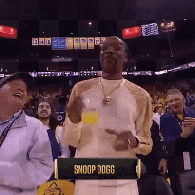 A Man In A Snoop Dogg Shirt Stands In Front Of A Crowd At A Basketball Game GIF
