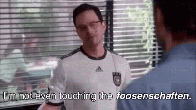 A Man In A Soccer Jersey Is Talking To Another Man In A Blue Shirt . GIF