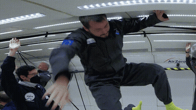 A Man In A Space Suit Is Being Lifted Up By Another Man In A Space Suit GIF