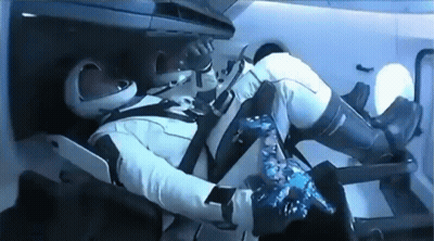A Man In A Space Suit Is Laying In A Chair In A Space Ship . GIF