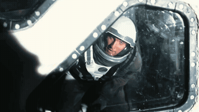 A Man In A Space Suit Is Looking Through A Window GIF