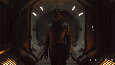 A Man In A Space Suit Is Standing In A Hallway That Says Alien On The Bottom GIF