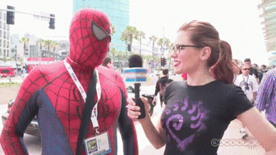 A Man In A Spider Man Costume Is Being Interviewed By A Woman GIF