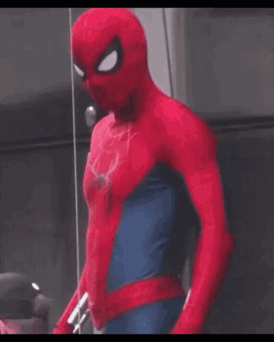 A Man In A Spider Man Costume Is Standing In Front Of A Glass Wall . GIF