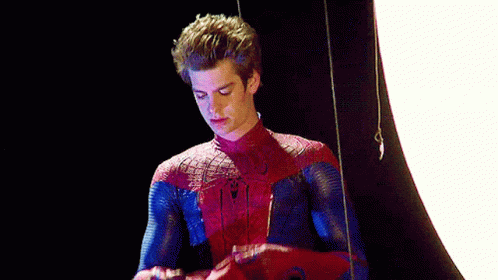 A Man In A Spider-Man Costume Is Standing In Front Of A White Light . GIF