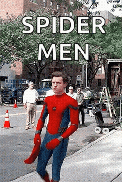 A Man In A Spider-Man Suit Is Walking Down A Sidewalk . GIF