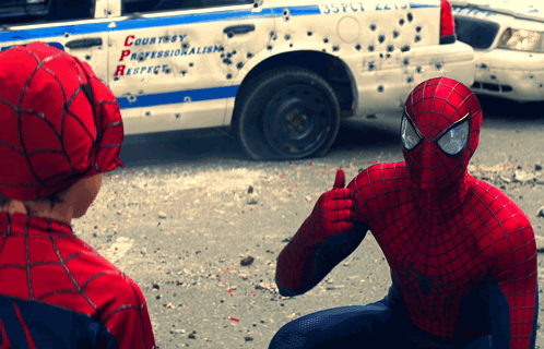 A Man In A Spiderman Costume Giving A Thumbs Up In Front Of A Police Car That Says Courtesy Professionalism Respect GIF