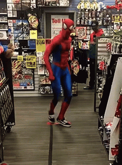 A Man In A Spiderman Costume Is Dancing In Front Of A Sign That Says Tell GIF