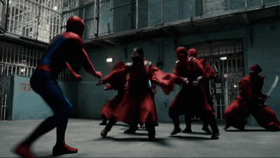 A Man In A Spiderman Costume Is Fighting A Group Of People In Red Robes GIF