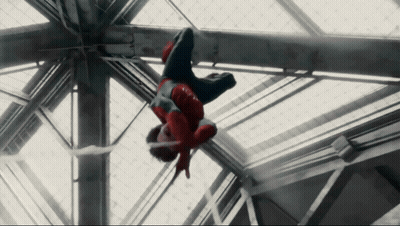 A Man In A Spiderman Costume Is Hanging Upside Down From A Metal Structure GIF