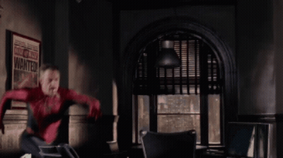 A Man In A Spiderman Costume Is Jumping In Front Of A Poster That Says Wanted GIF