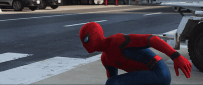 A Man In A Spiderman Costume Is Kneeling Down On The Side Of The Road GIF