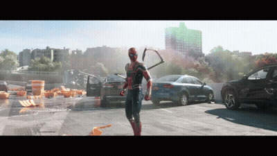 A Man In A Spiderman Costume Is Standing In A Parking Lot With Cars GIF