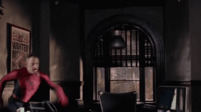 A Man In A Spiderman Costume Is Standing In Front Of A Poster That Says Wanted GIF