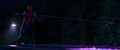 A Man In A Spiderman Costume Is Standing In Front Of A Street Light At Night GIF