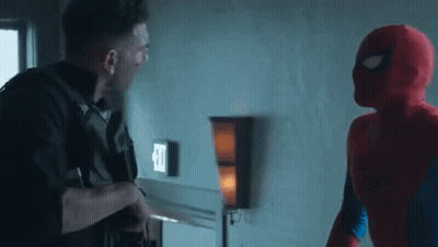A Man In A Spiderman Costume Is Standing Next To A Man In A Punisher Costume In A Room . GIF