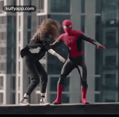 A Man In A Spiderman Costume Is Standing Next To A Woman On A Ledge . GIF