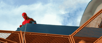 A Man In A Spiderman Costume Is Standing On Top Of A Fence GIF