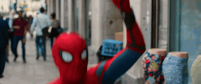 A Man In A Spiderman Costume Is Taking A Selfie On A City Street GIF
