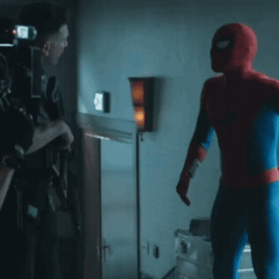 A Man In A Spiderman Costume Is Talking To Another Man GIF