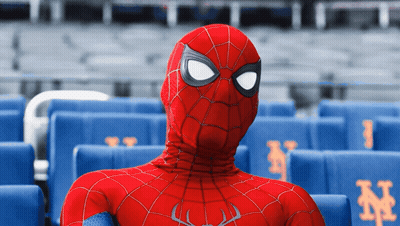 A Man In A Spiderman Costume Sits In A Stadium With Blue Seats With Ny On Them GIF