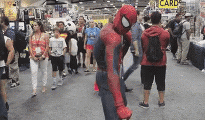 A Man In A Spiderman Costume Stands In A Crowd Of People GIF
