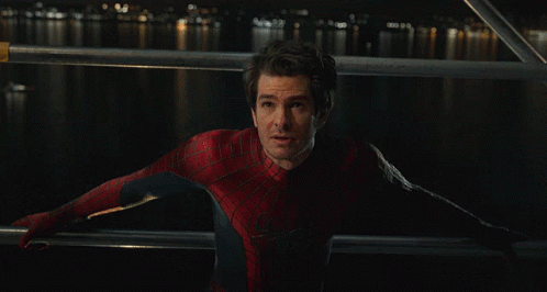 A Man In A Spiderman Costume Stands In Front Of A Body Of Water At Night GIF