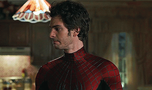 A Man In A Spiderman Costume Stands In Front Of A Lamp GIF