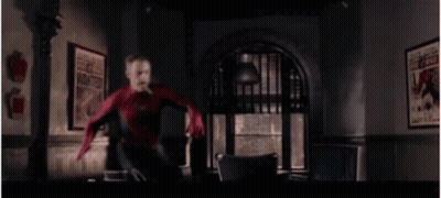 A Man In A Spiderman Suit Is Jumping In The Air In A Room . GIF