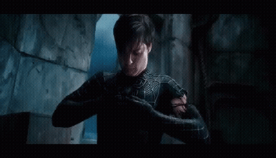 A Man In A Spiderman Suit Is Standing In A Dark Room With His Arms Outstretched . GIF