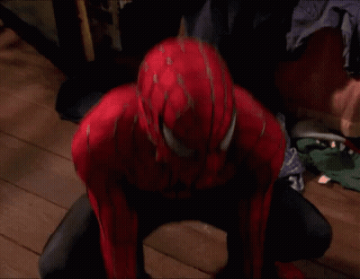 A Man In A Spiderman Suit Is Standing In A Room With A Brick Wall . GIF