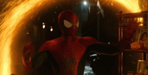 A Man In A Spiderman Suit Is Standing In Front Of A Fire GIF