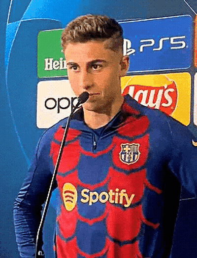 A Man In A Spotify Shirt Is Standing In Front Of A Microphone . GIF