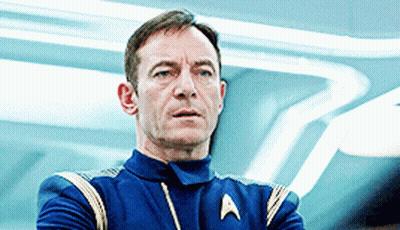 A Man In A Star Trek Uniform Is Looking At Something GIF