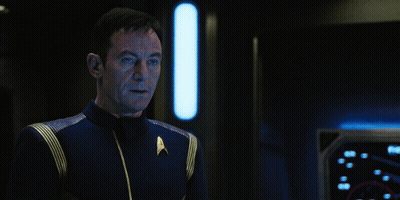 A Man In A Star Trek Uniform Stands Next To A Sign That Says Hold On A Second GIF