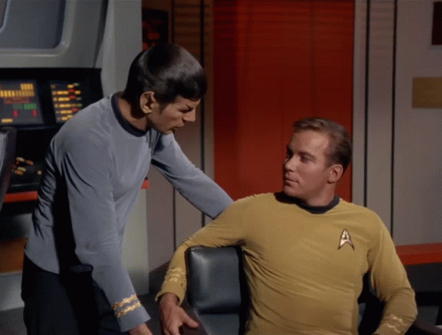 A Man In A Star Trek Uniform Stands Next To Another Man GIF