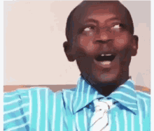 A Man In A Striped Shirt And Tie Is Making A Funny Face . GIF