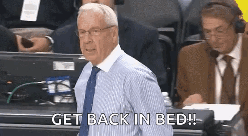 A Man In A Striped Shirt And Tie Is Standing In Front Of A Group Of Men And Says `` Get Back In Bed ! '' GIF