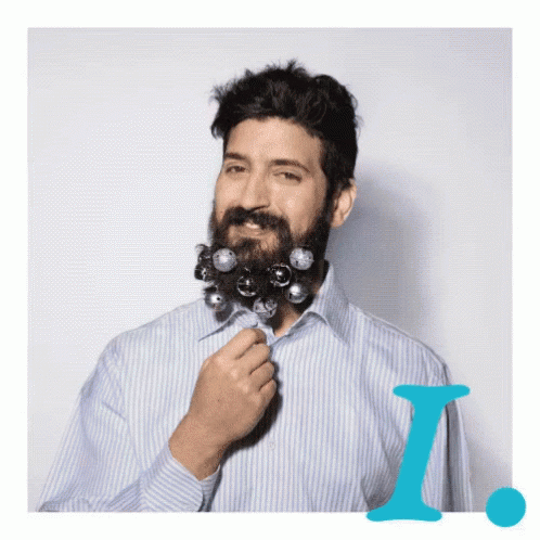 A Man In A Striped Shirt Has A Beard Decorated With Christmas Decorations GIF