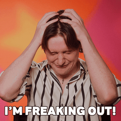 A Man In A Striped Shirt Has His Hands On His Head And The Words I 'M Freaking Out Above Him GIF